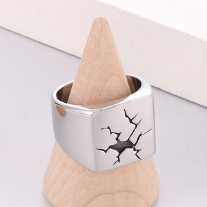 Detail of silver stainless steel ring with crack pattern on a wooden cone display