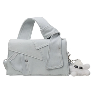Minimalist light blue denim crossbody bag with top knot handle and plush charm detail