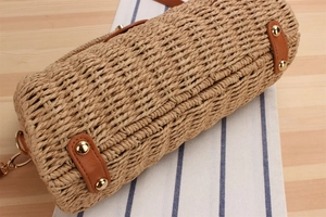 Detail of woven straw bucket bag with brown PU leather trim and gold metal rivets