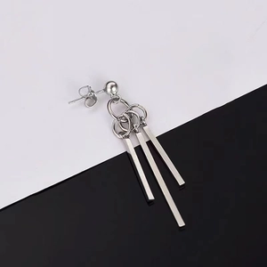 Macro shot of silver titanium fringe earrings with geometric bars on black and white background