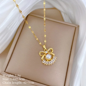 Detail view of gold bow necklace with pearl and rhinestones on beige jewelry box