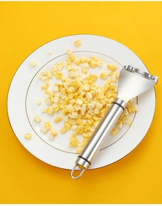Detail of stainless steel corn peeler with non-slip handle over corn kernels