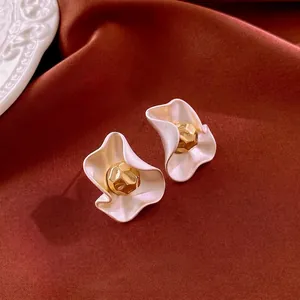 Minimalist white matte floral earrings with gold faceted center on silk background