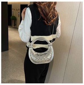 Detail of silver crescent moon handbag with diamond pattern texture and metal chain