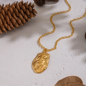 Collier vintage doré avec pendentif tête de Jésus et chaîne acier sur fond naturel