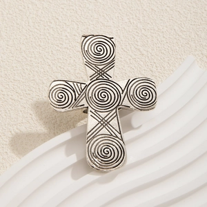 Retro silver cross ring with embossed spiral patterns on a white minimalist background
