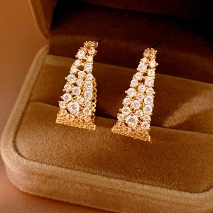 Dettaglio macro di orecchini a U placcati oro 18k con zirconi cubici brillanti incastonati
