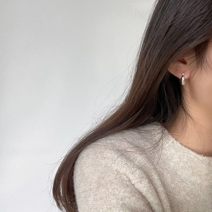 Minimalist silver huggie hoop earring worn by a model for a stylish everyday look