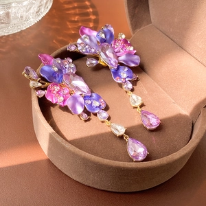 Macro detail of purple floral drop earrings with crystals in a velvet jewelry box