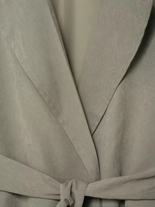 Detail of grey-green faux suede jacket showing textured lapel and belted waist knot
