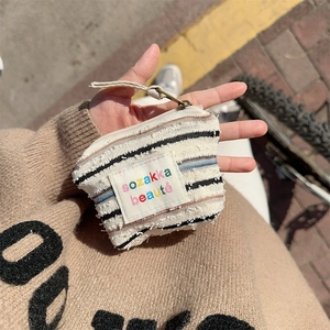 Close-up of a striped canvas mini coin pouch with zipper held in hand outdoors