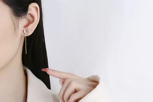 Close-up of a gold butterfly earring with sparkling zircon crystals and long tassel chain
