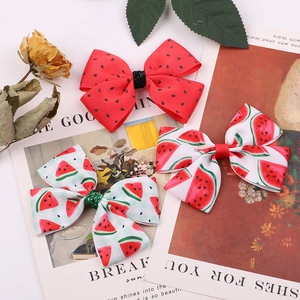 Three bow hair clips with watermelon print and red polka dots on a decorative card