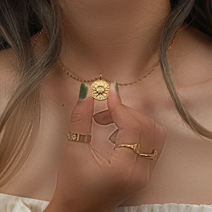 Vue détaillée du collier médaillon soleil doré vintage et bagues assorties sur un mannequin