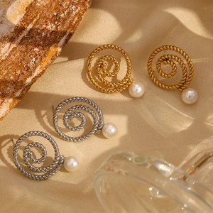 Detail of twisted gold and silver stud earrings with white pearls on elegant silk