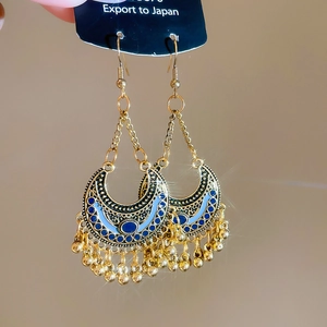 Detail of vintage bohemian crescent earrings with blue enamel and gold bead tassels