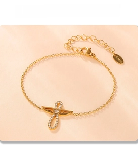 Vue détaillée du bracelet croix aile d'ange doré avec placage PVD et pierres brillantes