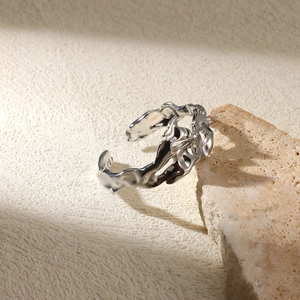 Detailed view of silver irregular liquid metal ring on a textured stone background