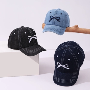 Three colors of denim kids baseball caps with bow embroidery on white geometric stands
