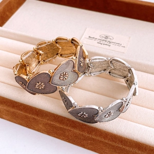 Close-up of gold and silver heart-shaped elastic bracelets with brushed metal texture