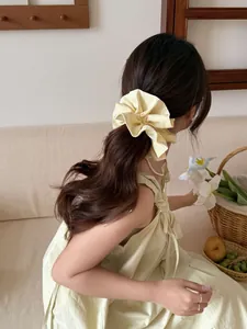 Detail of yellow striped fabric scrunchie with large bow design on model hair
