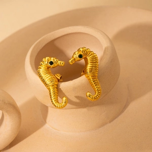 Golden seahorse stud earrings in titanium steel with dark gemstone eyes and fine texture