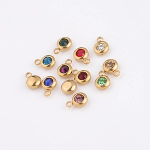 Macro shot of 12 multi-color birthstone charms in gold titanium steel on white surface