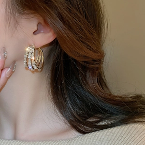 Gros plan d'élégantes boucles d'oreilles créoles dorées triple rang avec oxydes de zirconium