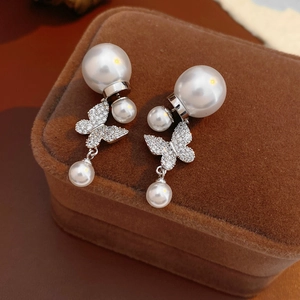 Detail view of vintage pearl butterfly earrings with zircons on a brown velvet box