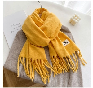 Detail of yellow wool-like scarf showing soft texture and delicate fringe tassels