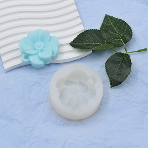 Macro detail of 3D flower silicone mold with finished blue resin floral pendant