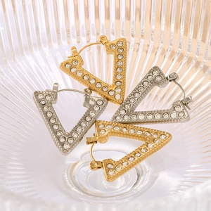 Minimalist V-shaped gold and silver earrings with rhinestones in a glass bowl