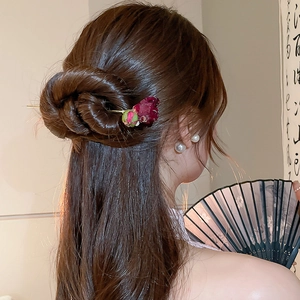 Dettaglio del fermaglio per capelli con rosa vintage, asta dorata e perle su chignon