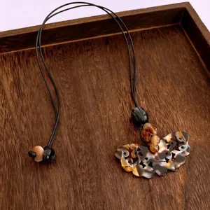 Collier vintage avec pendentif papillon évidé, perles d'ambre et cordon ciré