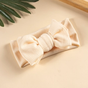 Detailed texture of beige knit baby headband with a large double-layer bow design