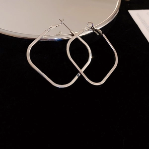 Macro shot of silver geometric square hoop earrings on a black velvet background