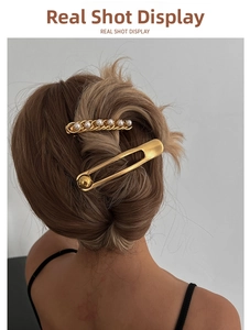 Detail shot of elegant golden hairpin set with white pearls on model hair style