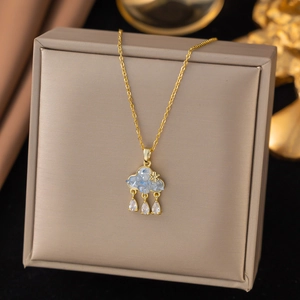 Macro detail of golden cloud pendant with blue texture and crystal raindrop charms