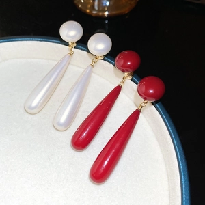 Detailed close-up of 18k gold plated earrings featuring pearl and red drop pendants