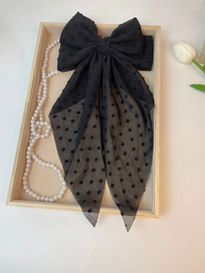 Detail of elegant black polka dot tulle hair bow clip with long streamers on wooden tray