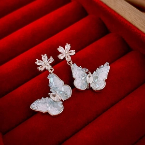 Macro shot of butterfly crystal drop earrings in a red velvet jewelry gift box