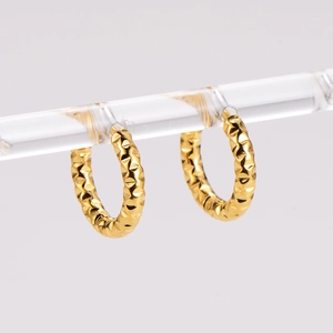 Detailed view of gold hoop earrings with textured diamond-cut facets on an acrylic stand