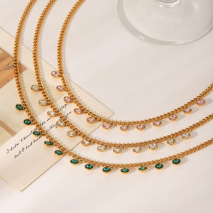 Detailed view of triple-layered gold necklaces with green and pink zircon gemstone charms