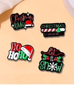Detailed view of four Christmas themed enamel pins with artistic festive lettering