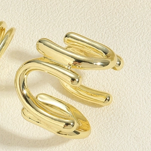 Macro shot of minimalist gold croissant-style cuff ring on a textured cream surface