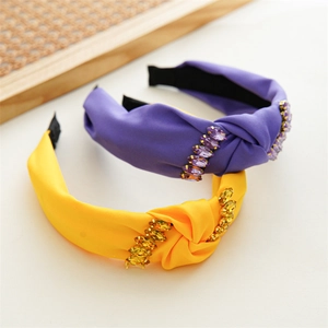 Detail view of purple and yellow knotted headbands with shiny rhinestone embellishments