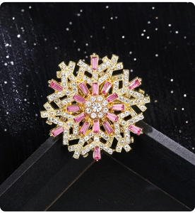 Macro detail of snowflake brooch with gold setting and sparkling pink rhinestones