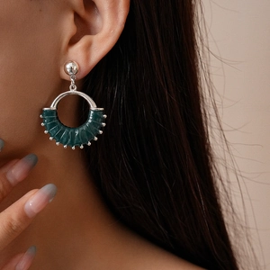 Close-up of a model wearing dark green leather hollow circle earrings with silver accents