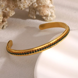 Detailed close-up of 18K gold-plated stainless steel cuff with green pavé zircon stones