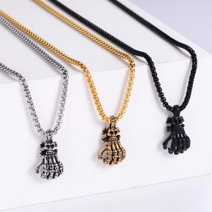 Close-up of gothic skeleton hand pendants in silver, gold, and black stainless steel